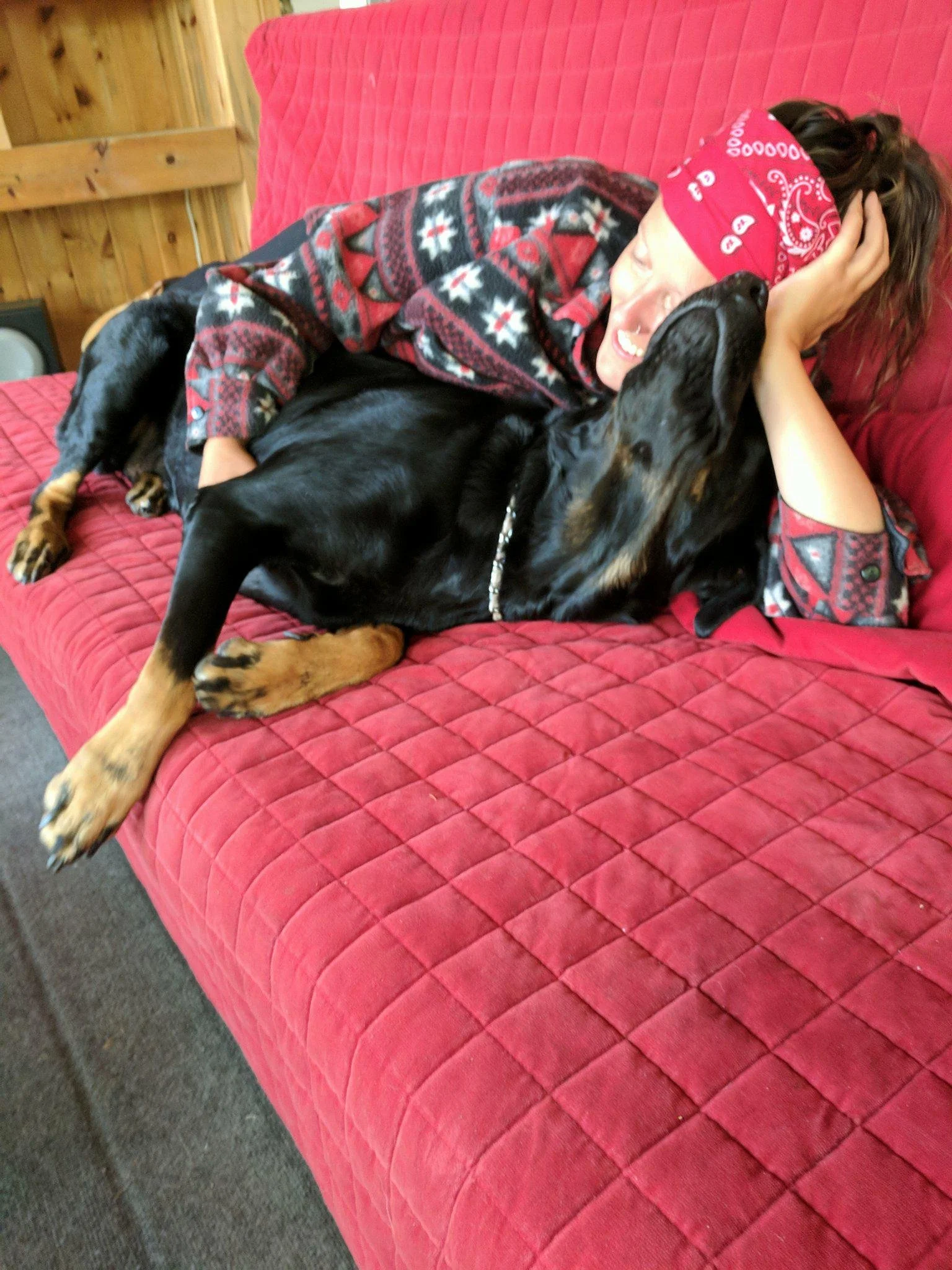 Founder relaxing on a red couch with a black dog — the real life behind the brand